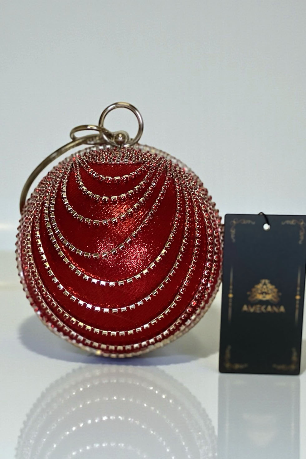 Red globe clutch with layered rhinestone chain drape and crystal-trim edge close-up front view
