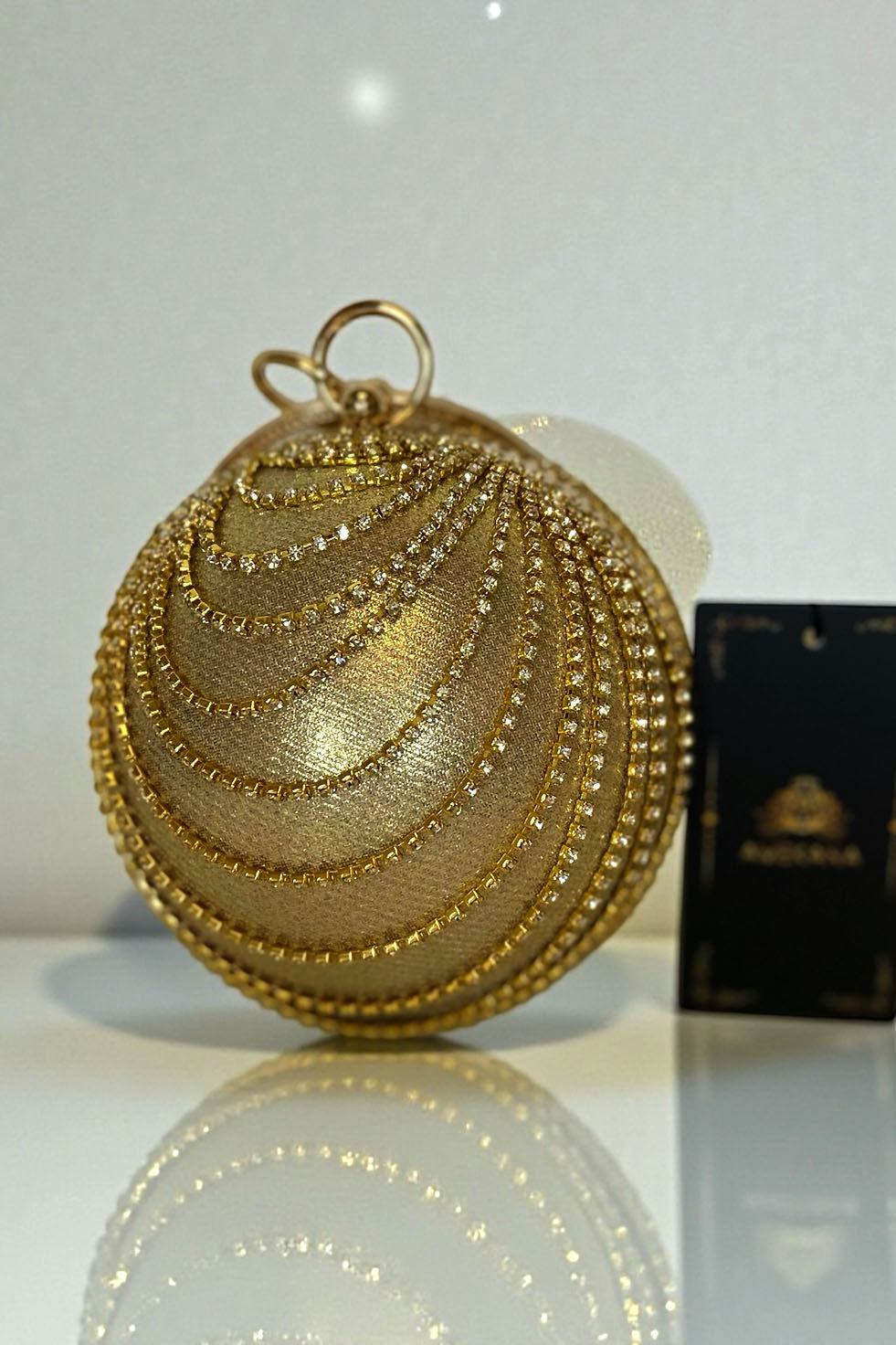 Close-up of champagne gold spherical evening bag with rhinestone draped chains and crystal trim luxury accessory