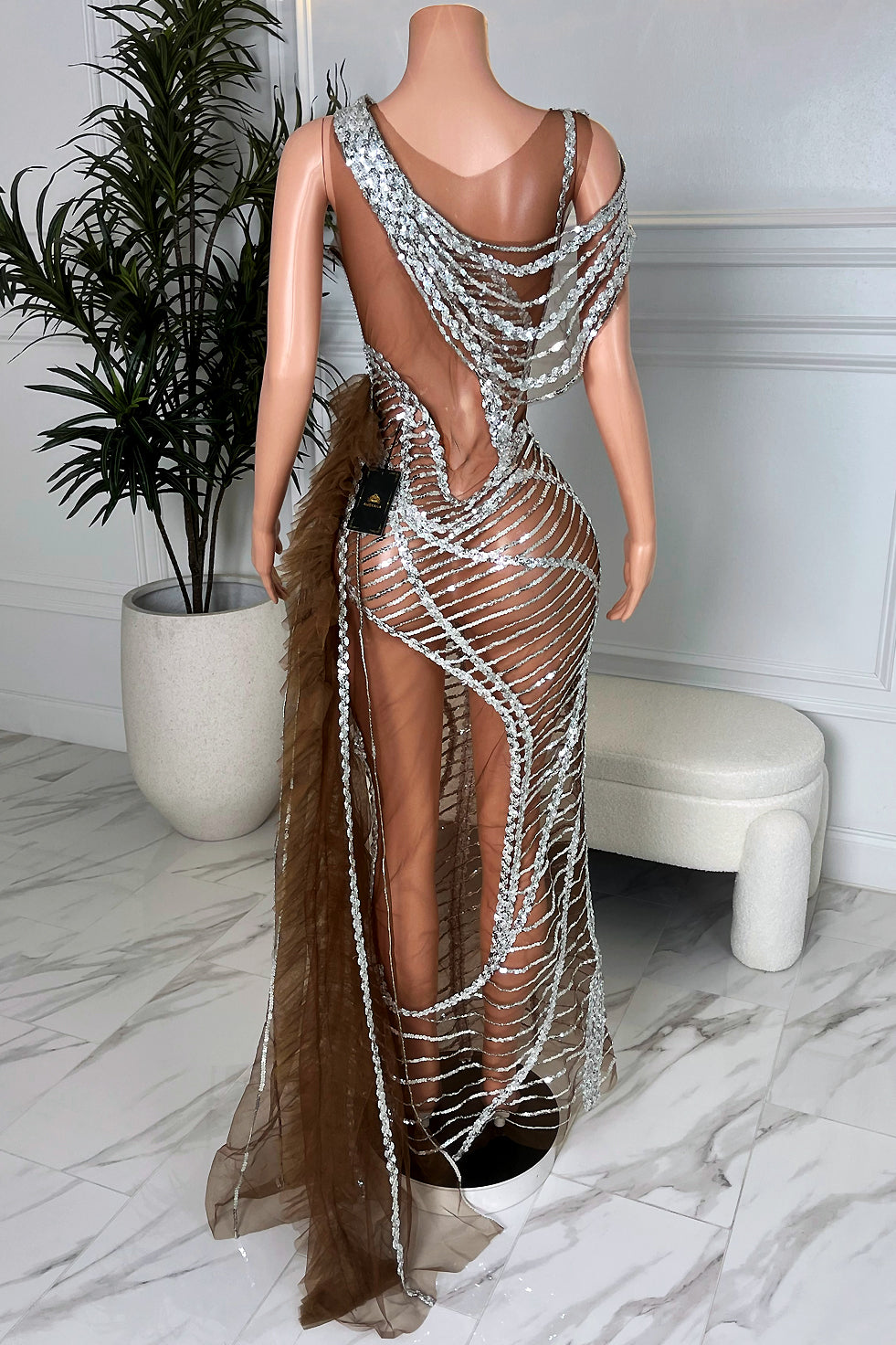 Back view of brown and silver sequin asymmetrical evening dress with draped sequin straps and sheer back