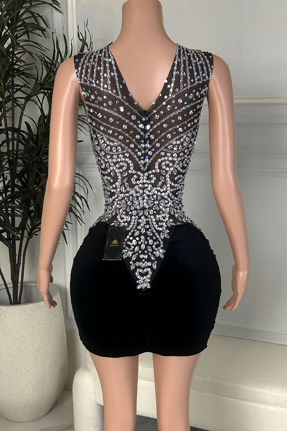 Black velvet mini dress with silver rhinestone embellished back and fitted ruched skirt, back view.