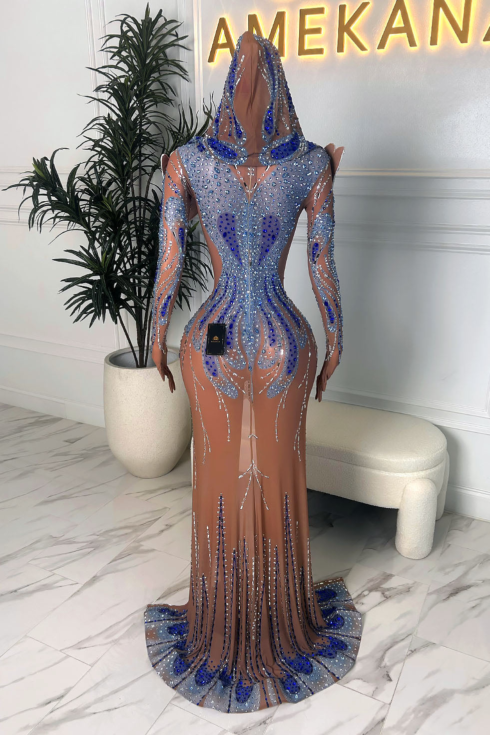 ack view of a nude illusion blue and silver rhinestone gown showing the hooded veil detail, long sleeves, and sparkling train.