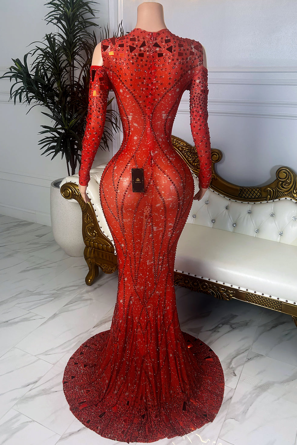 Back view of a red sheer mesh crystal dress with long sleeves, cold-shoulder cutouts, center zipper closure, rhinestone embellishments, and flared hem.