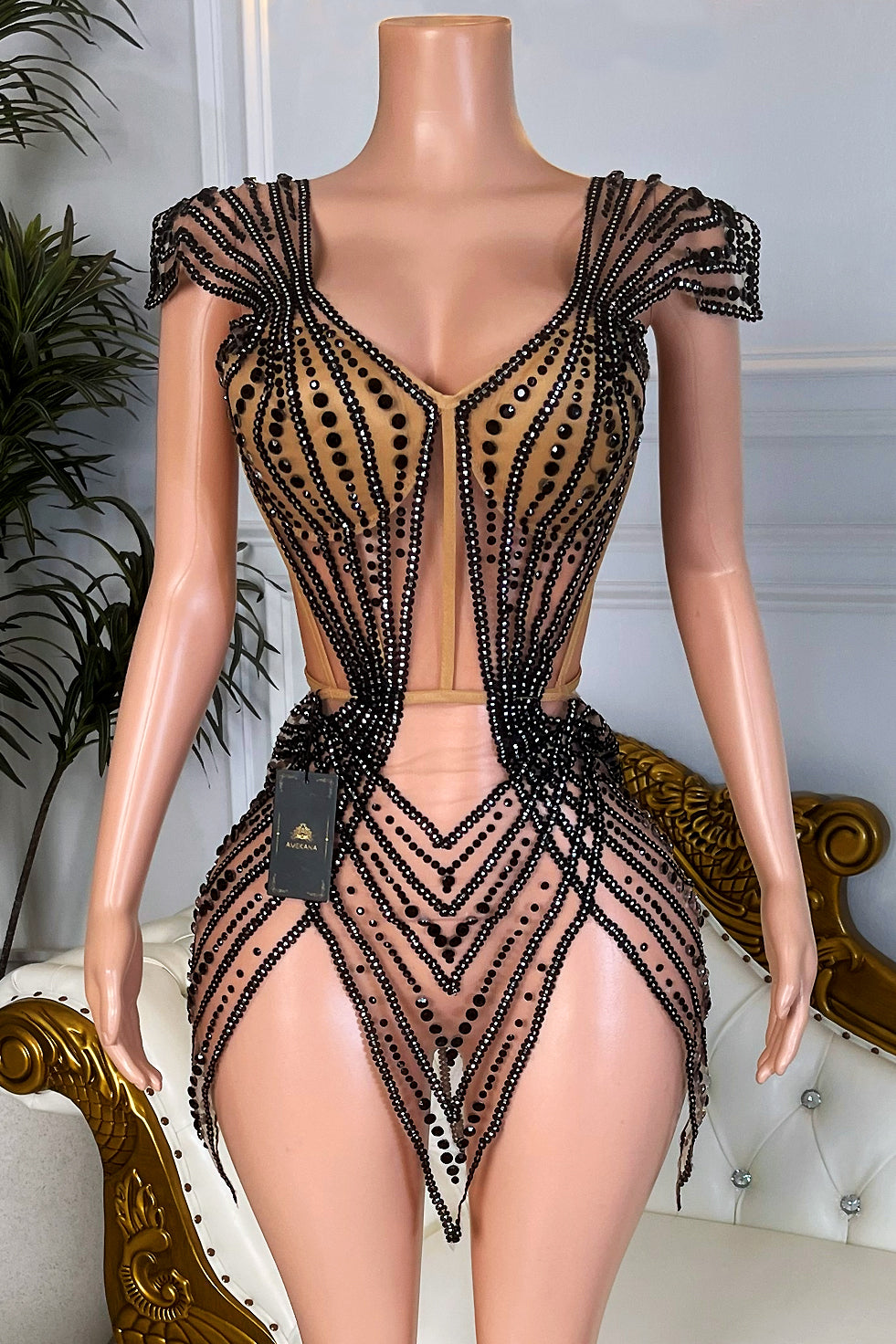 Front view of nude mesh mini dress with black rhinestone corset and asymmetrical pointed hem