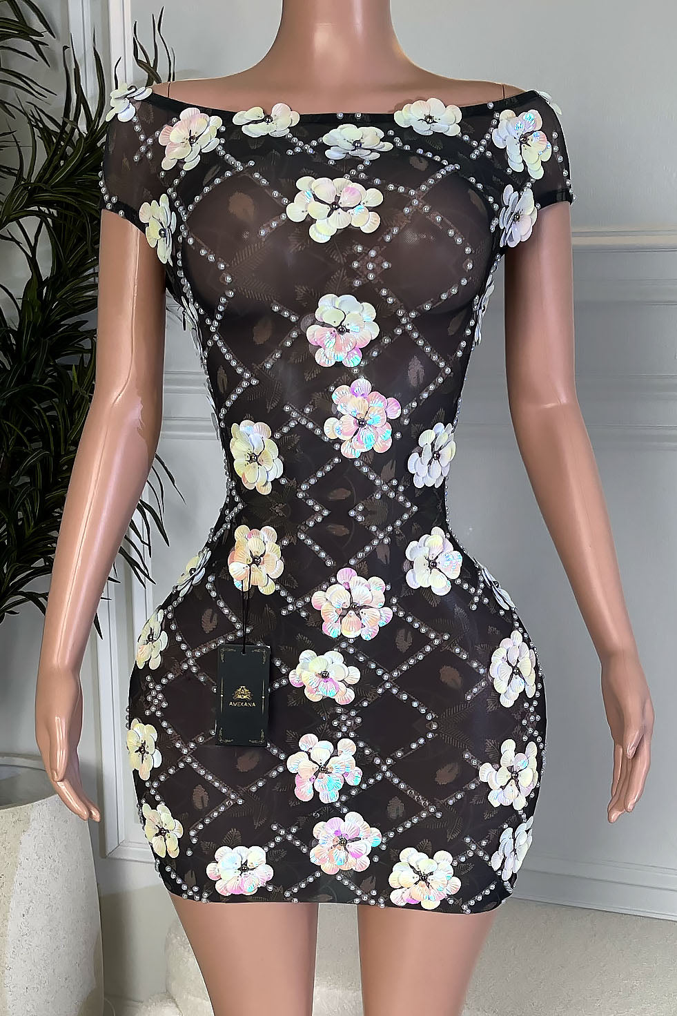 Black sheer off shoulder bodycon mini dress with rhinestone lattice and iridescent floral sequin appliqués, front view on mannequin