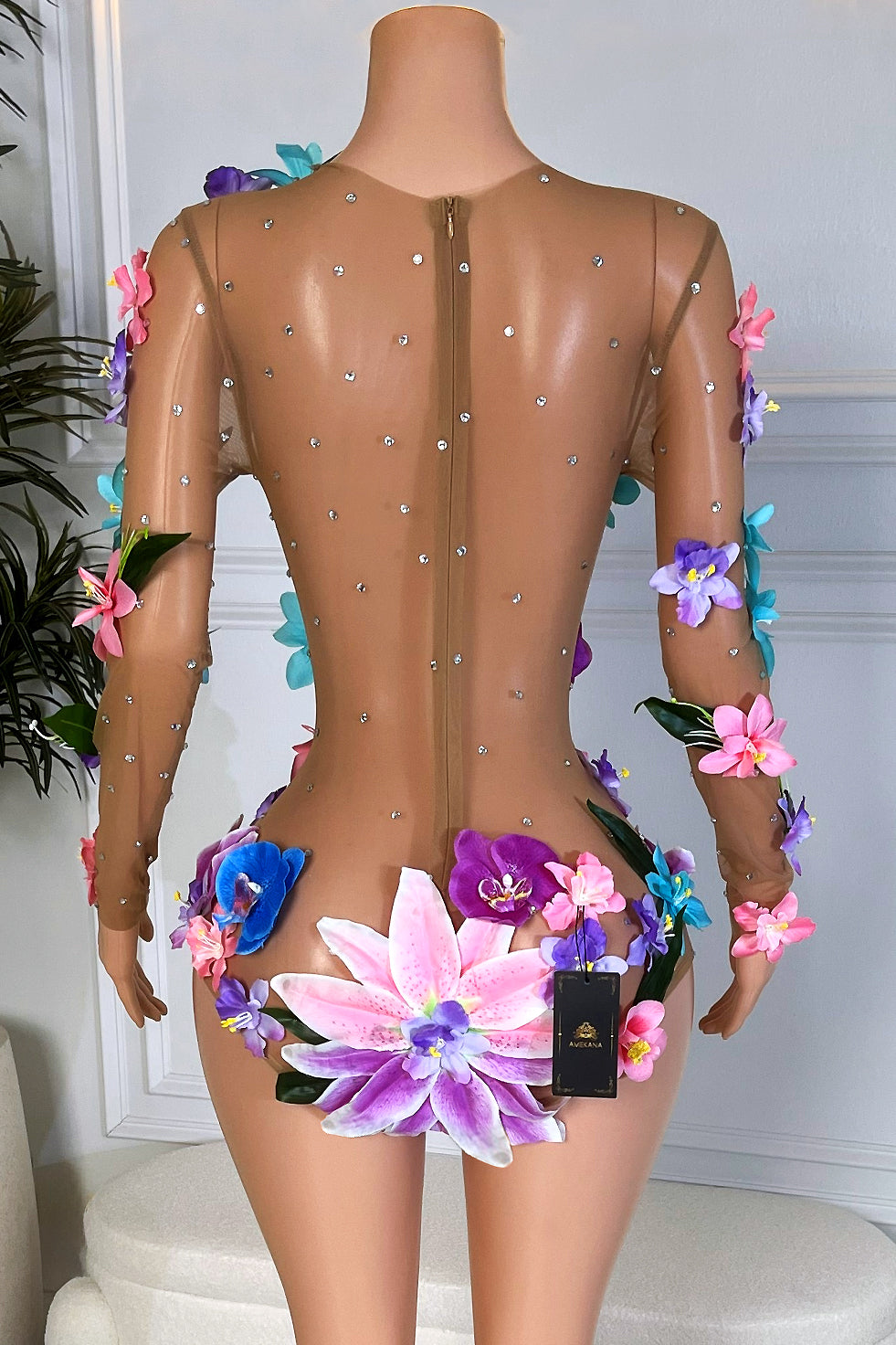 Nude mesh floral playsuit with scattered rhinestones and large 3D flowers placed over the hips and back, shown on a mannequin, back view