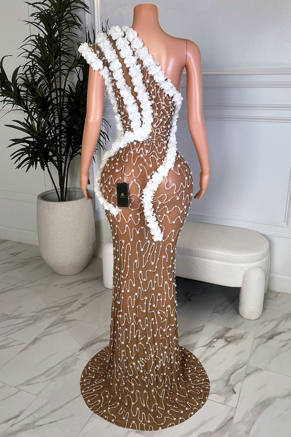 Back view of white floral nude illusion maxi gown with asymmetrical design, pearl detail, and dramatic train by Amekana.