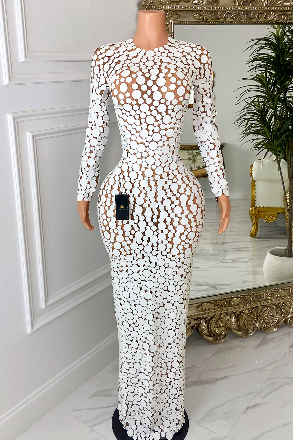 Front view of nude illusion mesh maxi dress with white circle appliqué, long sleeves, high neckline, and body-hugging fit