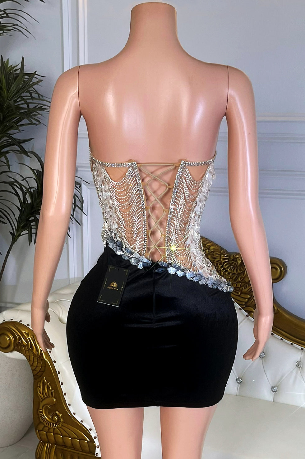Back view of black velvet mini dress featuring lace-up corset back and crystal fringe detail