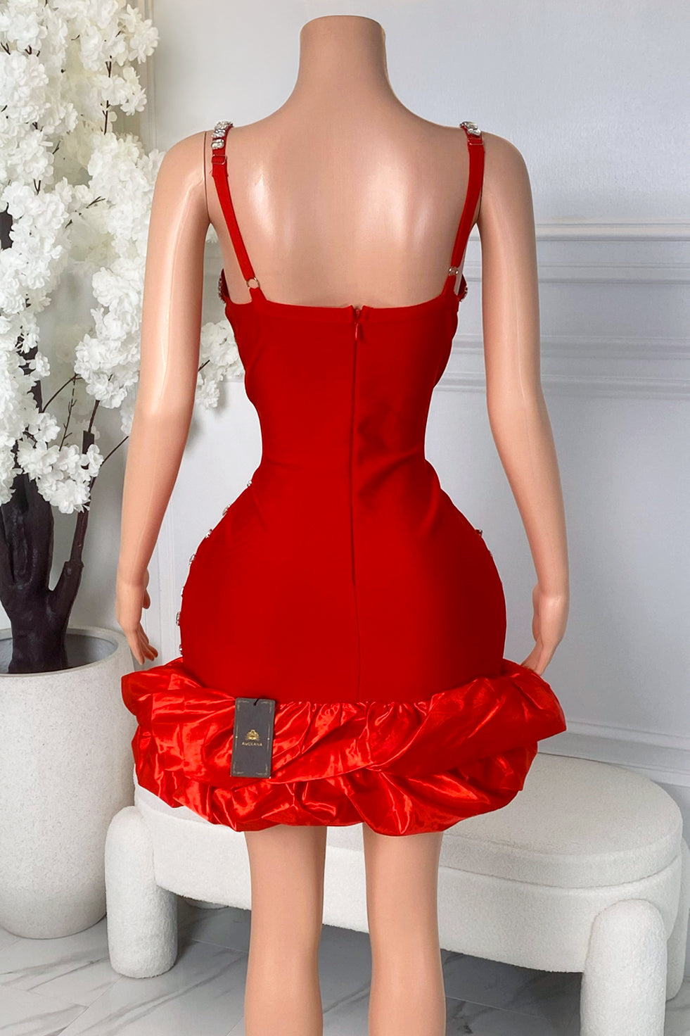Back view of red mini dress with back zipper closure, rhinestone straps, smooth red fabric, and statement bubble hem