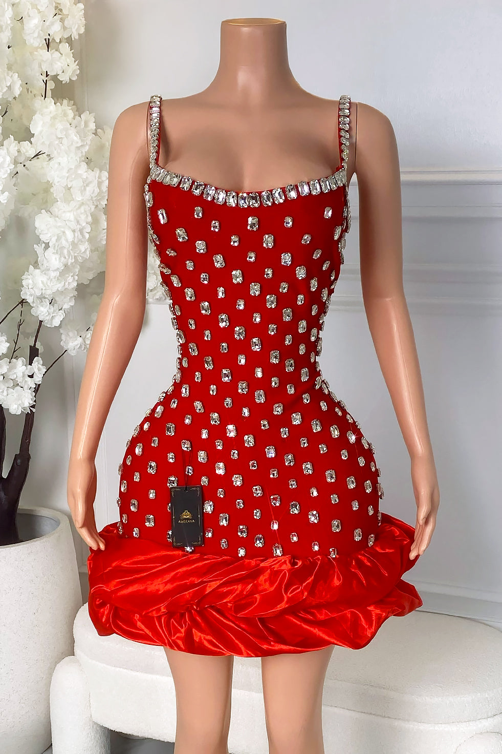 Front view of red rhinestone mini dress with square neckline, rhinestone straps, sparkling rhinestone details, and bubble hem