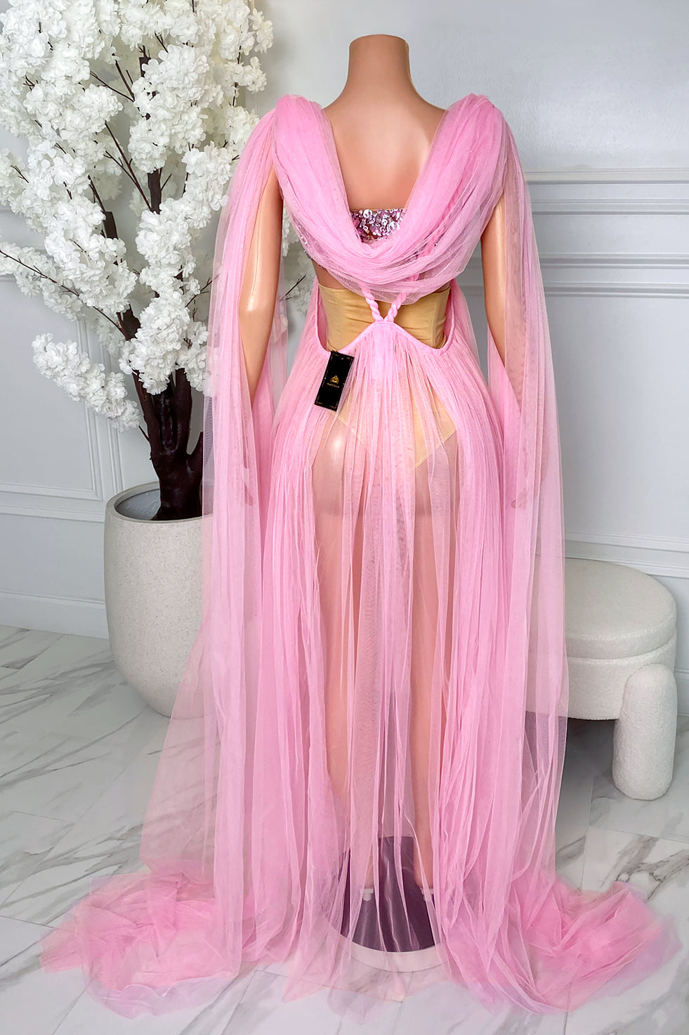 Back view of Elara Pink Rhinestone Tulle Maxi Dress featuring an open back, flowing pink tulle cape panels, braided back detail, and sheer tulle maxi skirt