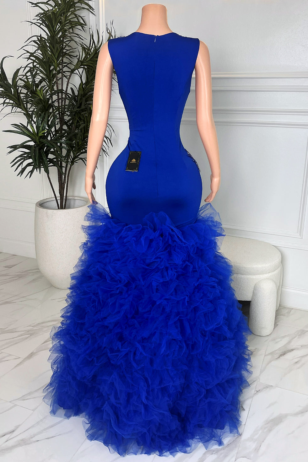 Back view of royal blue floor-length mermaid gown with fitted silhouette and dramatic tulle ruffle skirt, formal prom evening dress