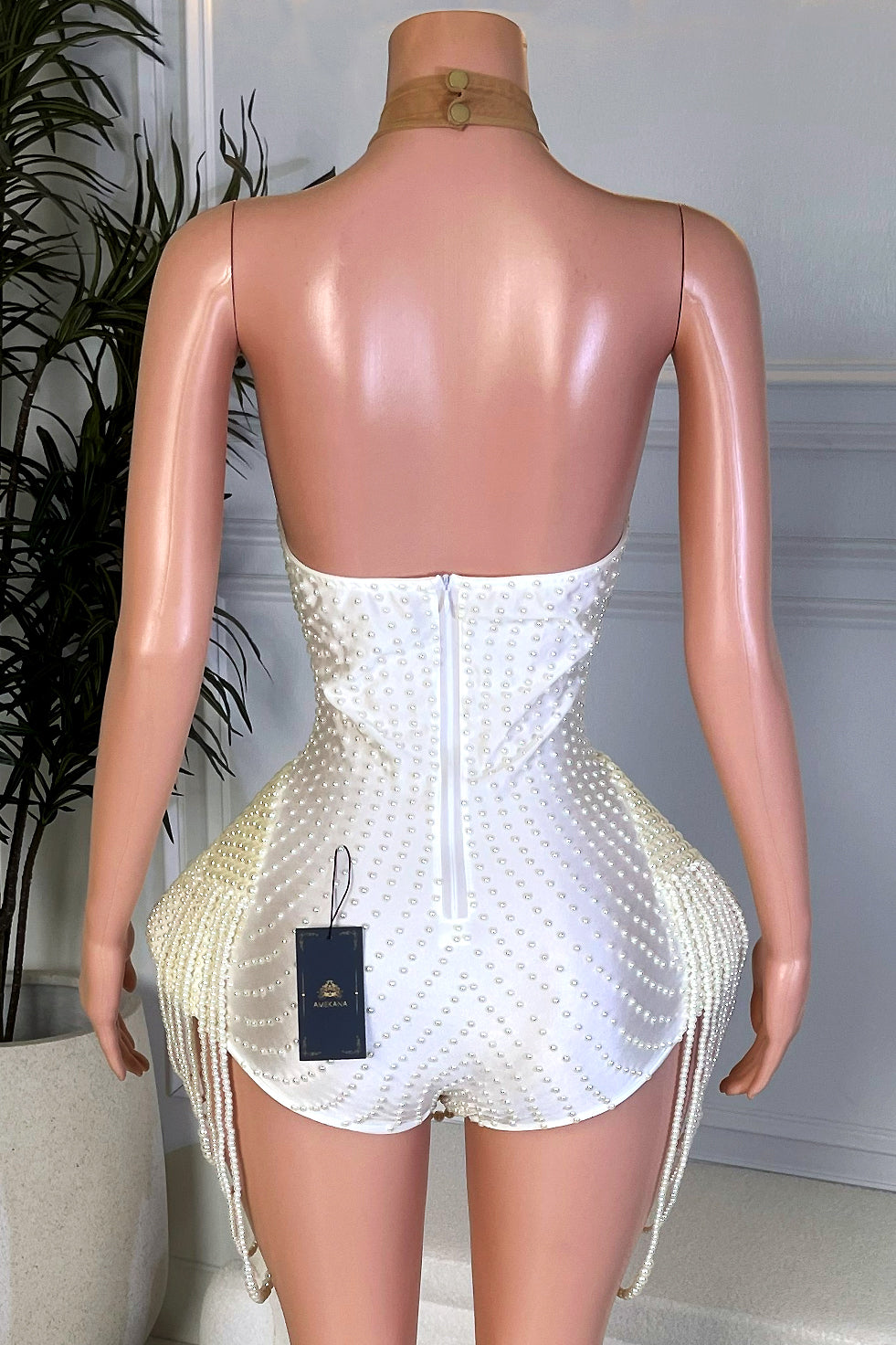 Back view of ivory pearl embellished playsuit with halter neckline, open back, and draped pearl tassel sides by Amekana.