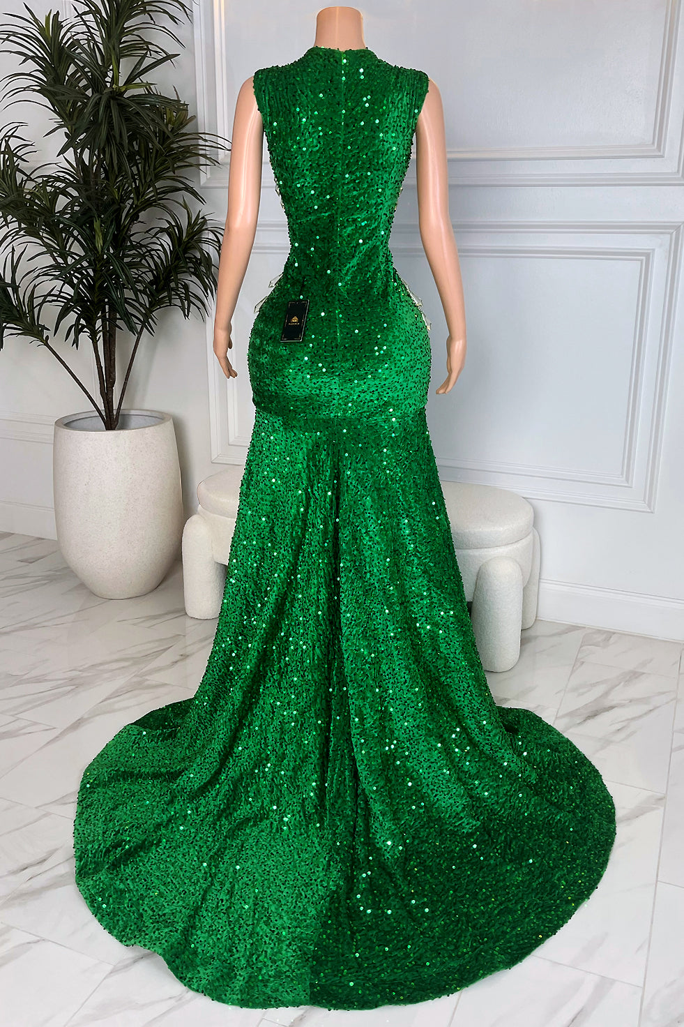 Back view of emerald green sequin mermaid gown with sleek fitted silhouette and long sweeping train, full sparkle finish for formal evening wear.