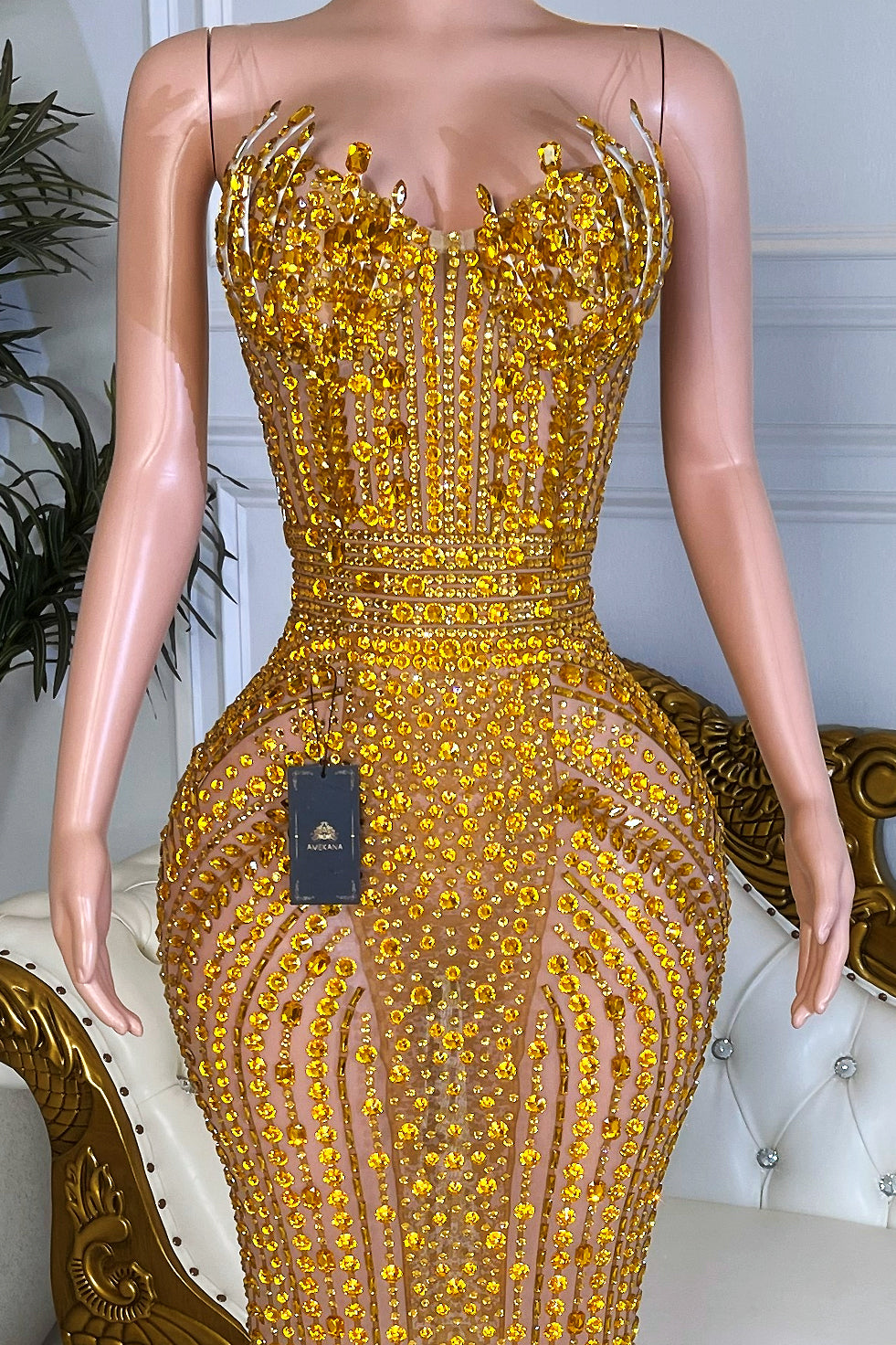 Close-up of strapless gold rhinestone corset bodice with intricate crystal embellishments on nude illusion fabric