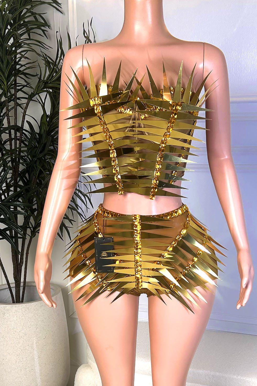 Front view of a gold metallic two-piece set with a strapless structured top, matching shorts, and mirrored spike detailing