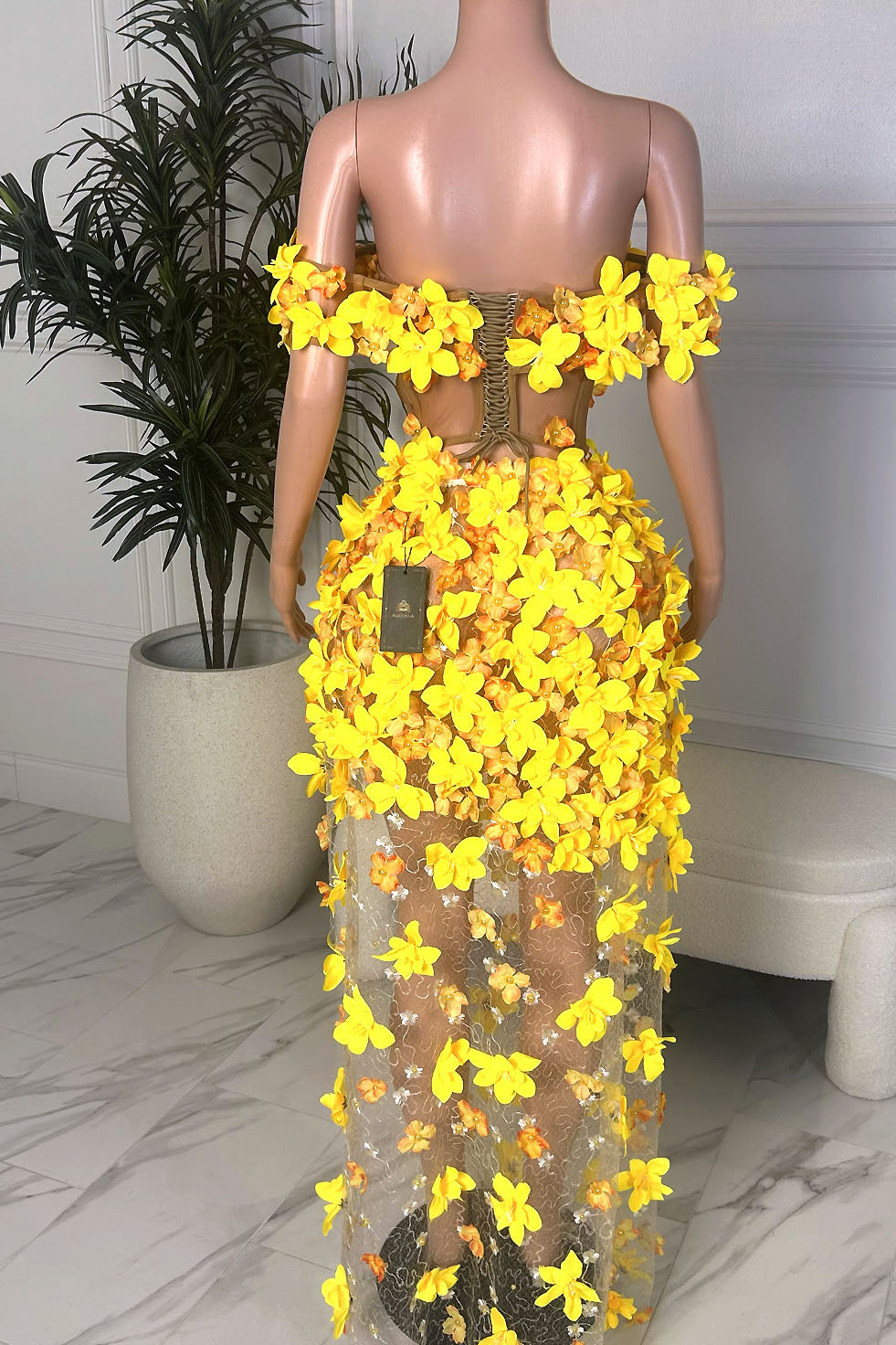 Back view of a yellow floral sheer skirt set featuring a lace-up back top, off shoulder sleeves, and floor-length floral skirt