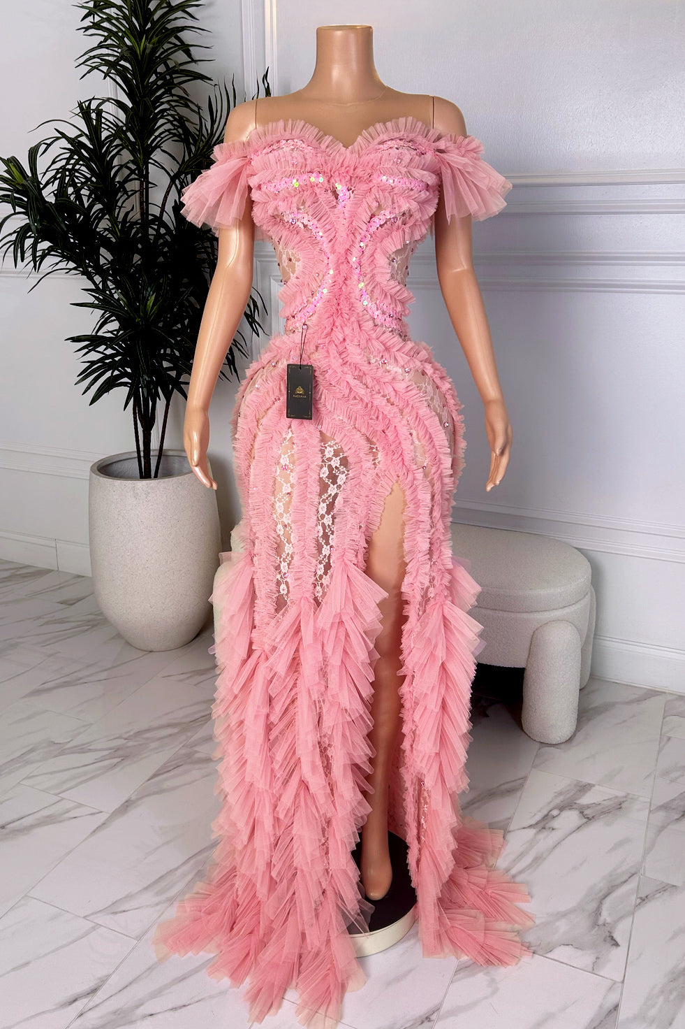 Front view of a soft pink off-shoulder evening dress with layered ruffle appliqué, illusion lace panels, and a high slit