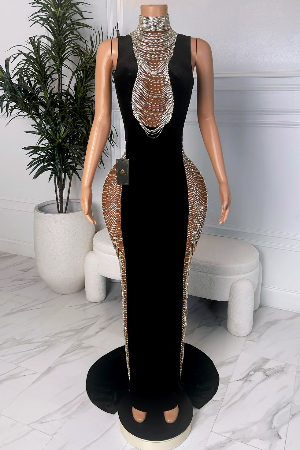 Front view of black fitted evening dress with crystal high neckline, cascading crystal chest detail, and sculpted crystal side panels