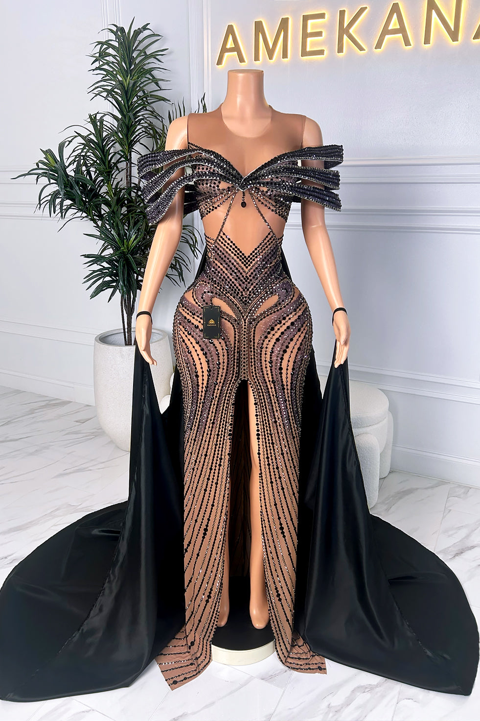 Back view of black illusion dress with open teardrop back, lace-up corset detail, and flowing black cape train