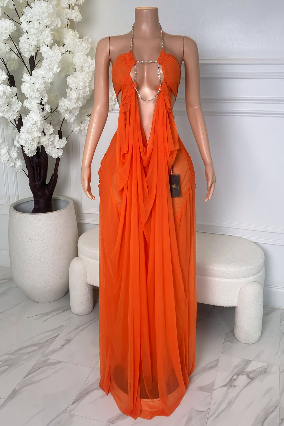 Front view of orange sheer maxi dress with rhinestone chain neckline, deep open front, gathered bust, and flowing draped fabric