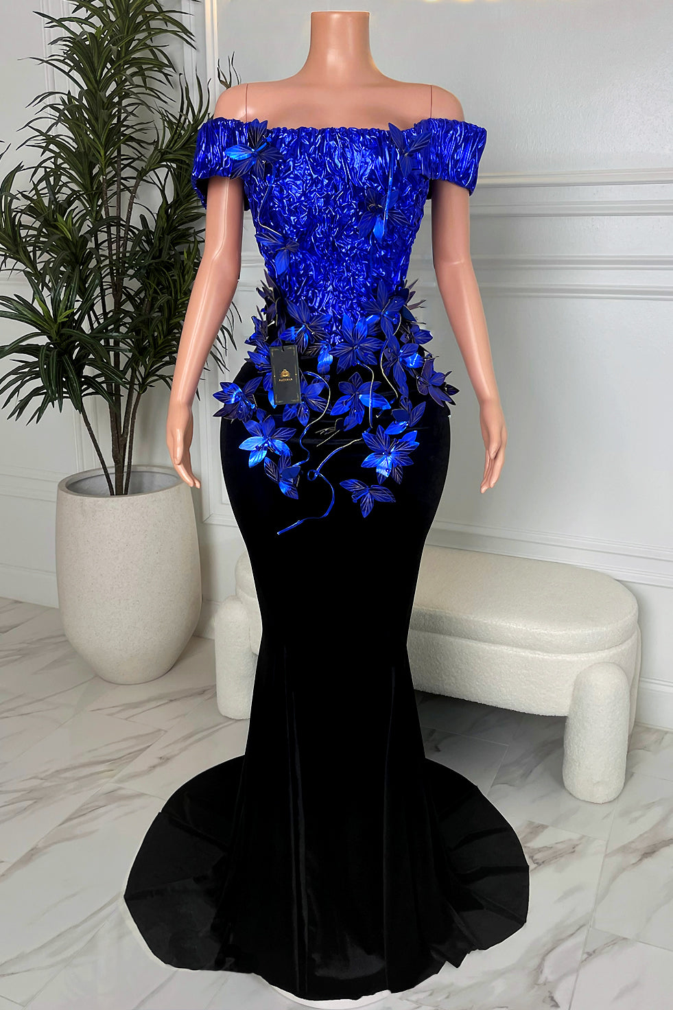Model mannequin wearing a cobalt blue chrome flower off shoulder bodice with black velvet mermaid maxi skirt and small train, Amekana evening gown.