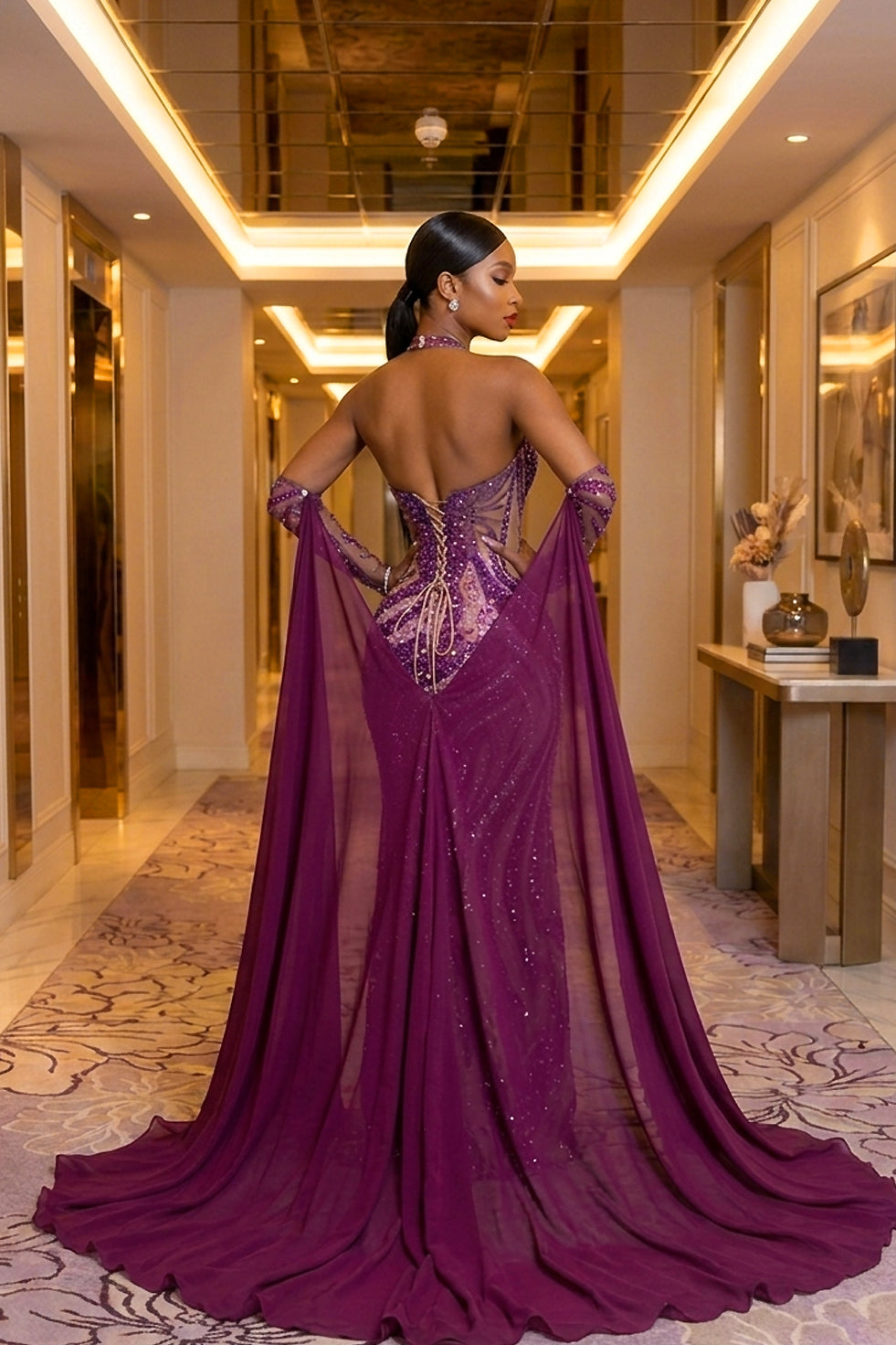 Back view of a purple rhinestone dress with open lace-up back and dramatic flowing cape panels in a luxury hotel hallway