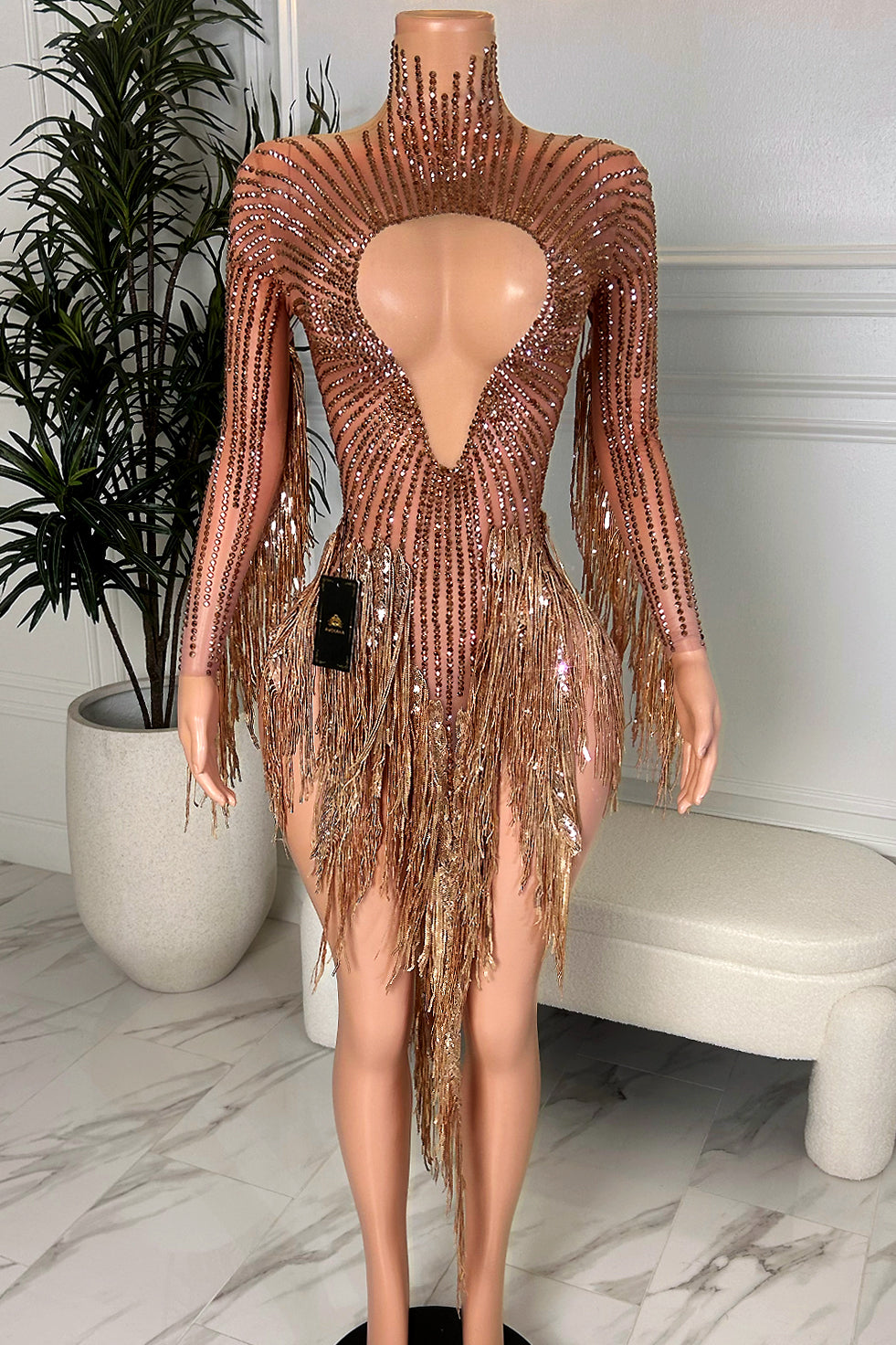 Rose gold rhinestone tassel mini dress with long sleeves, high neck keyhole cutout, and sparkling fringe detail on a nude illusion base, front view.