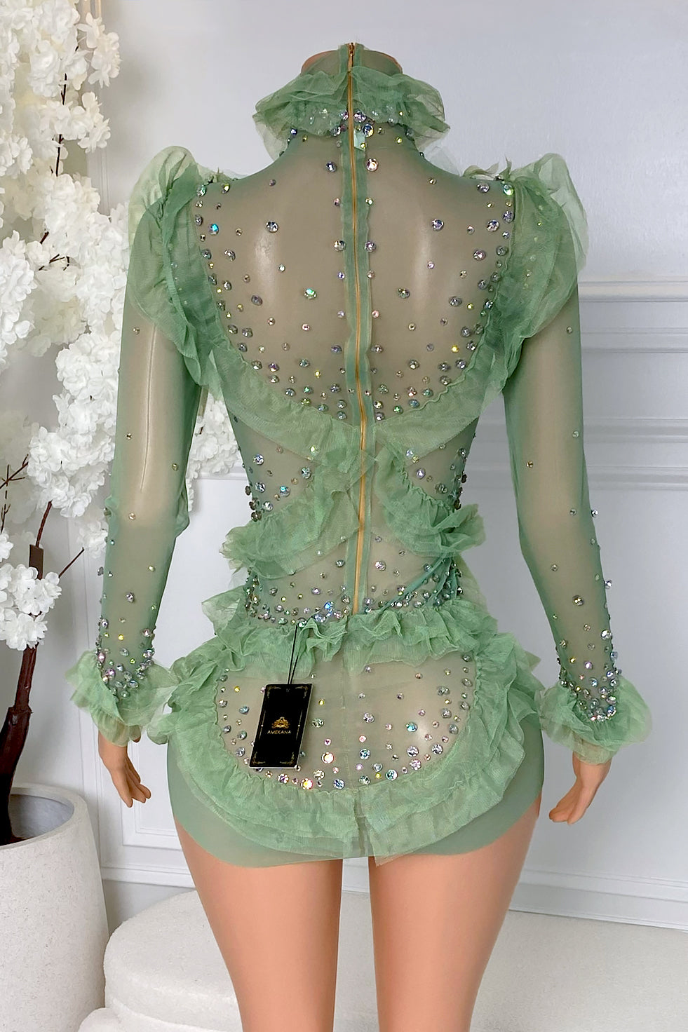 Back view of green ruffle rhinestone mini dress with sheer mesh, sparkling rhinestones, ruffle trim, long sleeves, and back zipper closure