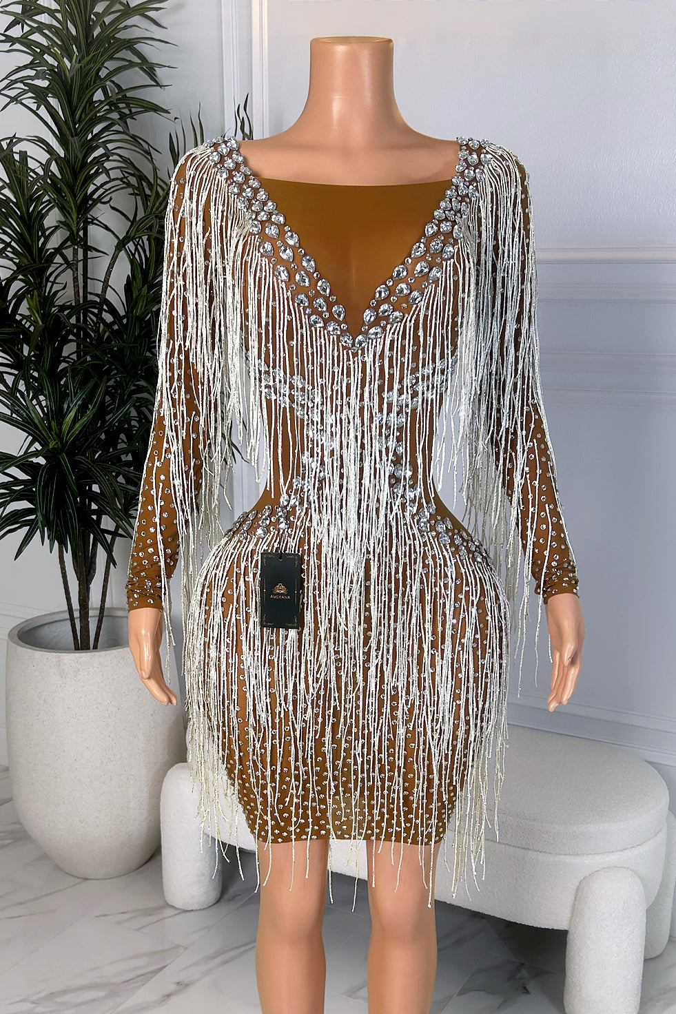 Back view of brown long sleeve mini dress with silver rhinestones, white fringe details, V-back design, and fitted silhouette.