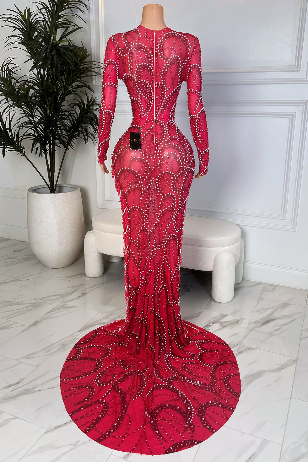 Back view of the same fuchsia rhinestone mesh maxi gown showing the full length fitted silhouette, zipper closure, and heavily embellished train pooling on the floor 