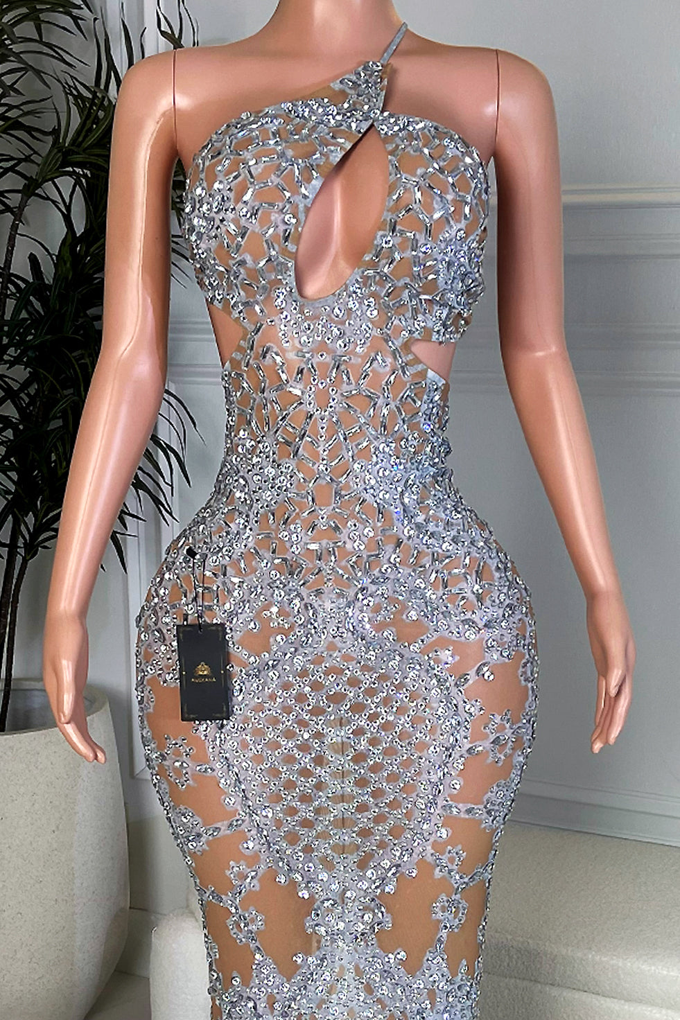 Close-up of silver rhinestone mosaic bodice with one-shoulder neckline and teardrop keyhole cutout on nude mesh