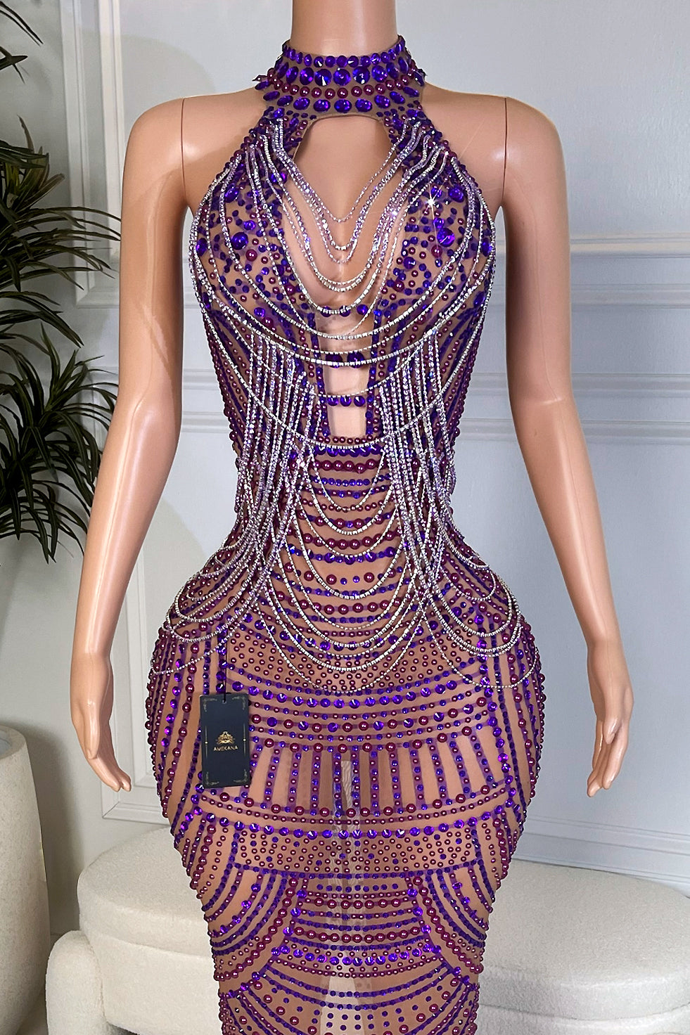 Close up of the halter neckline and bodice of a purple rhinestone illusion dress with layered crystal chains draping over the chest