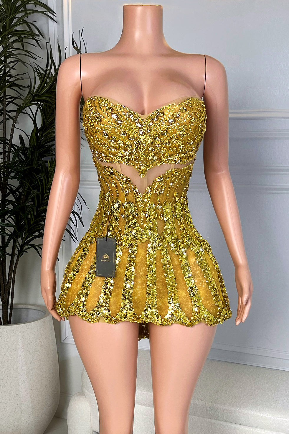 Model mannequin wearing a sparkly gold rhinestone corset mini dress with sweetheart neckline, sculpted waist cutout, and bubble hem, Amekana luxury birthday and party dress