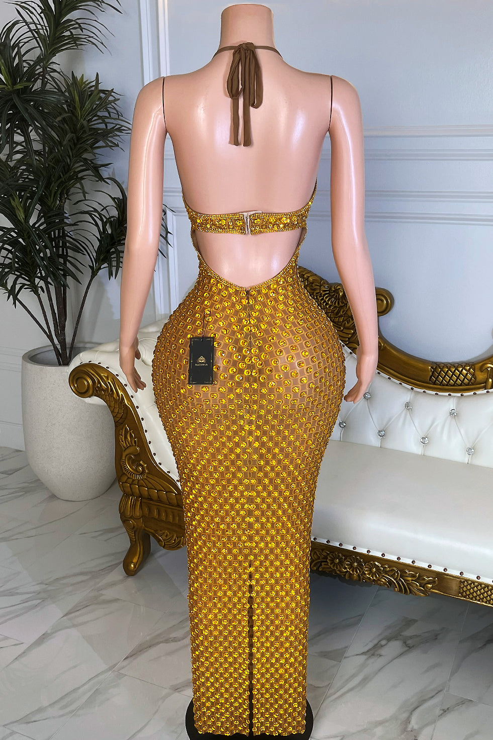 Back view of gold rhinestone halter bodycon maxi dress with open back, rhinestone belt and floor length skirt