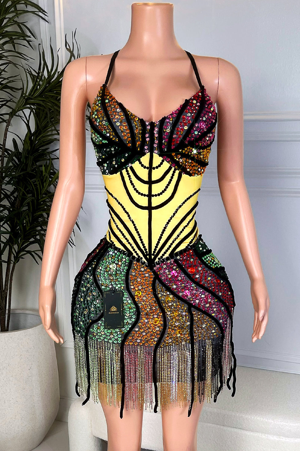 Front view of a multicolor rhinestone butterfly mini dress with yellow corset bodice, black contour lines, stained glass style skirt, and crystal fringe hem from Amekana.”