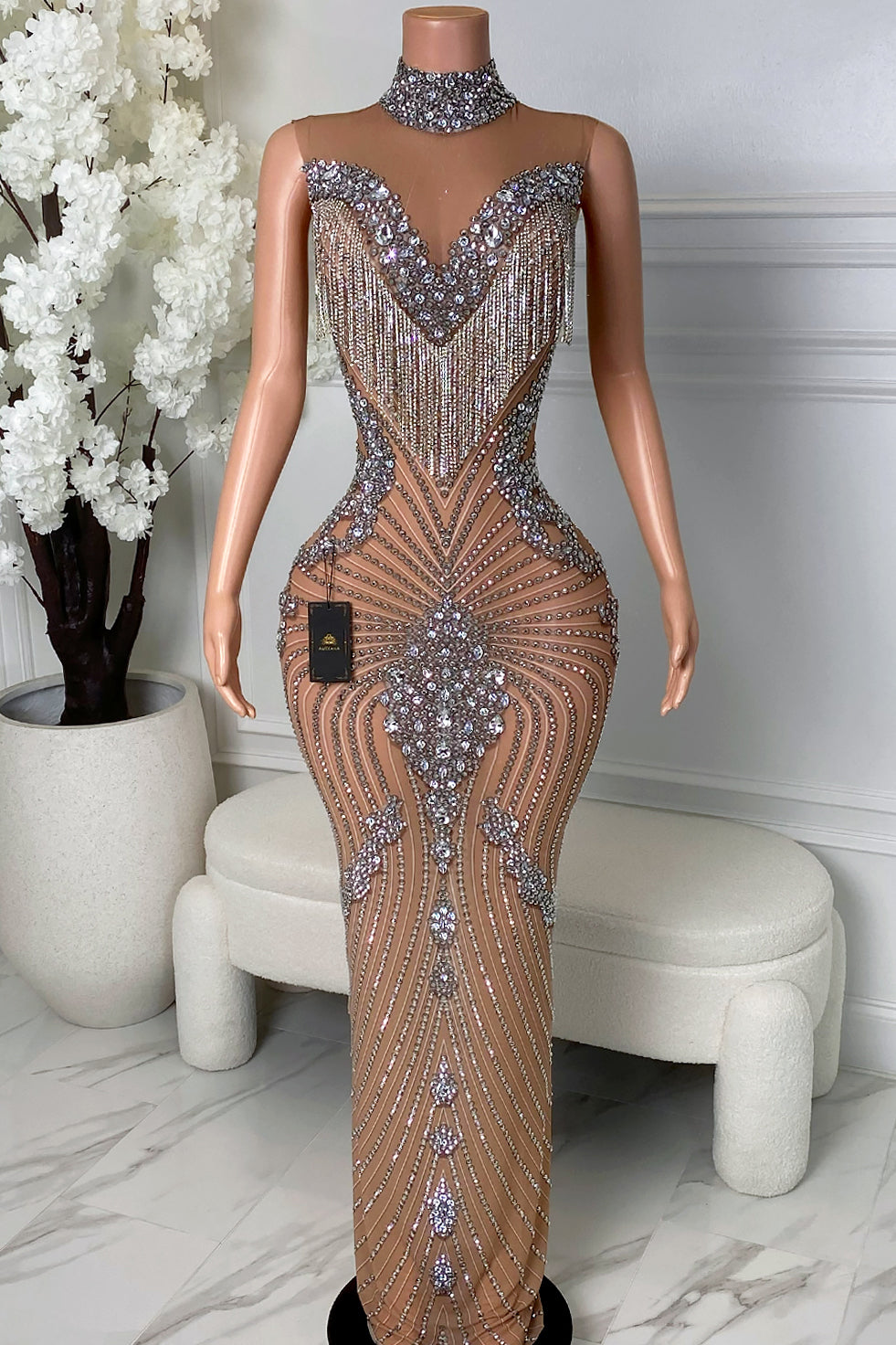 Front view of nude rhinestone tassel maxi dress with silver rhinestones, high choker neckline, sheer mesh base, deep illusion front, and rhinestone tassel fringe