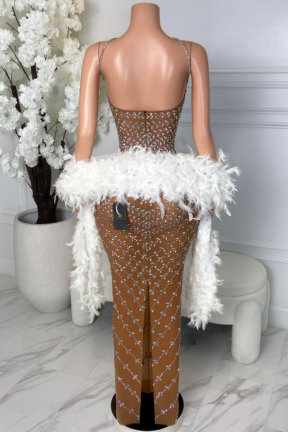 Back view of nude rhinestone boa dress with open back, back zipper closure, silver rhinestone pattern, back slit, and white feather boa