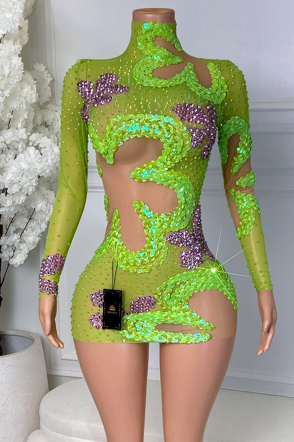 Front view of the Zavina Lucky Charm Mini Dress featuring lime green sheer mesh, green sequin swirl details, purple crystal floral accents, long sleeves, and bold cutouts.